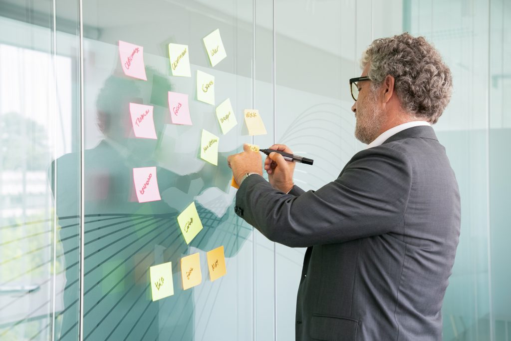 Mężczyzna podpisujący dokumenty z użyciem kolorowych markerów, planujący projekt w biurze jako część planowania sukcesji.